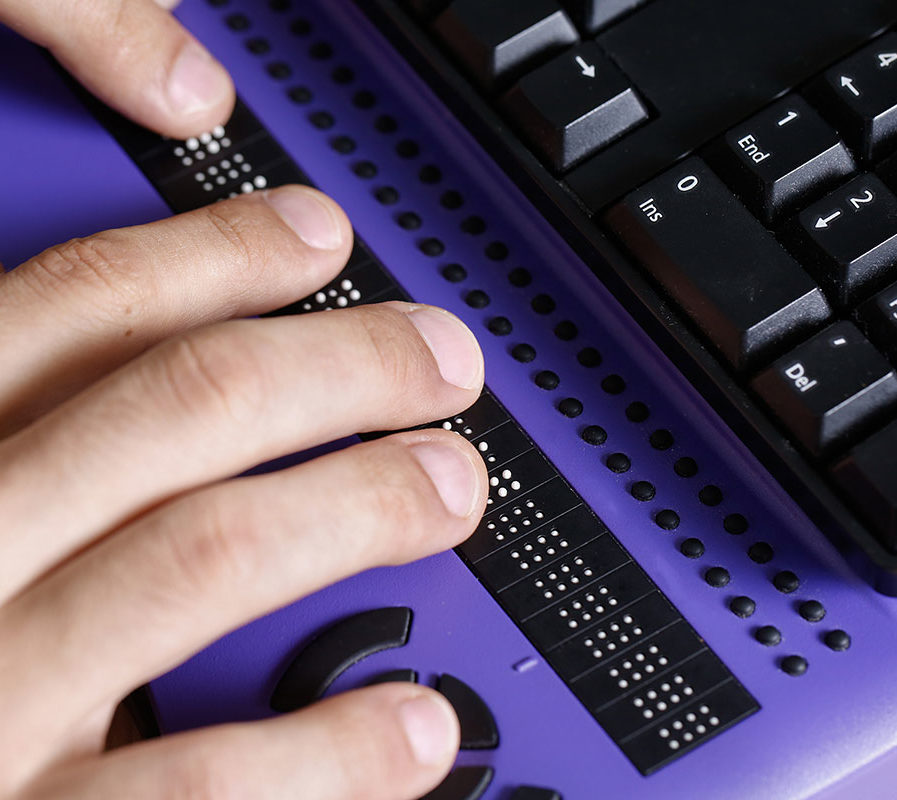 Person reading braille through digital braille assistive device