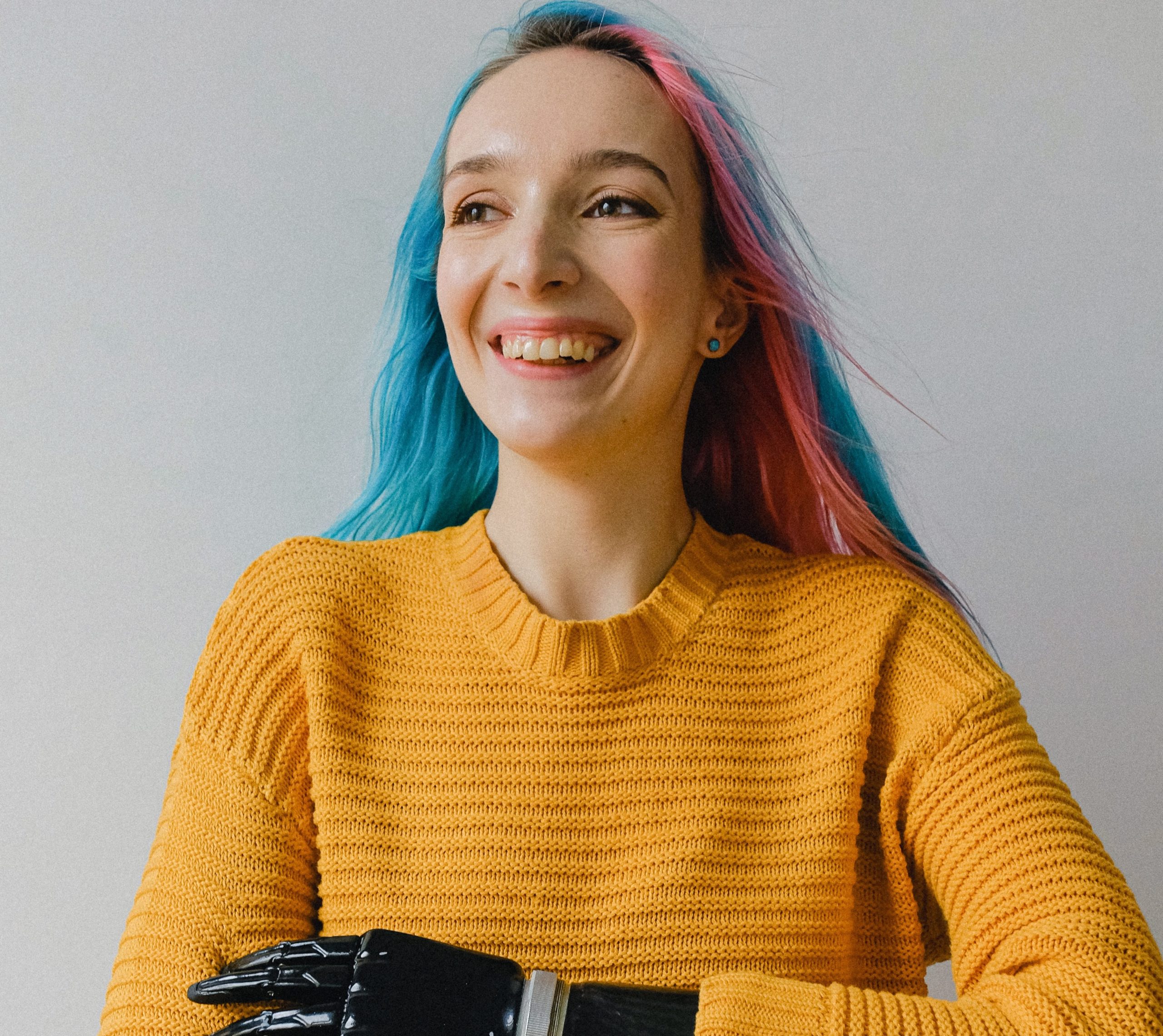 Young woman with prosthetic arm with brightly coloured sweater and hair