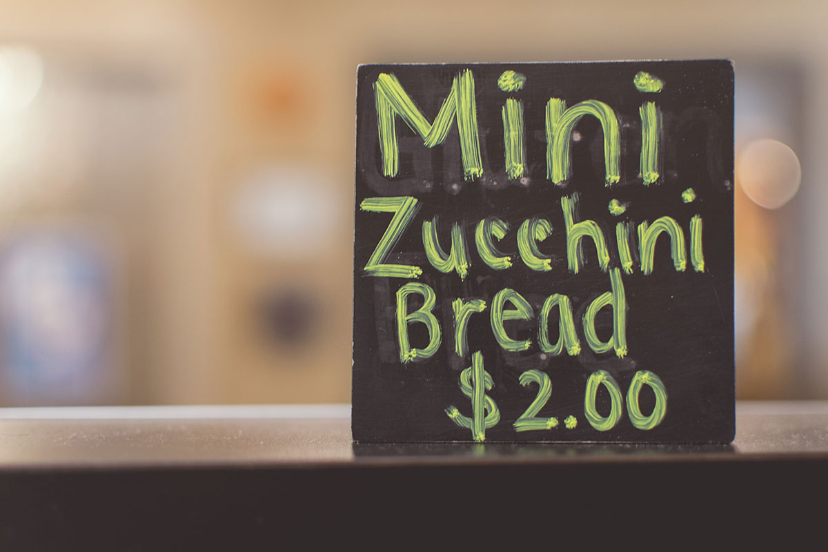 A handwritten sign on a table advertising mini zucchini bread for $2